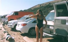 a woman in a bathing suit standing next to cars