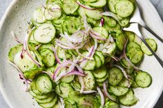 a white bowl filled with cucumbers and onions on top of a gray table