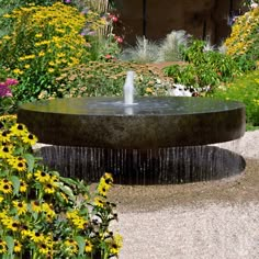 a water fountain surrounded by flowers in a garden