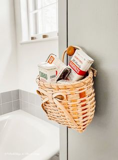 a wicker basket hanging on the wall next to a bathtub filled with food