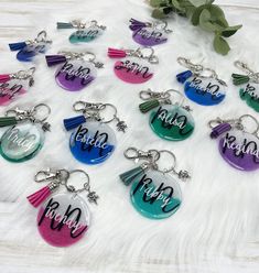 twelve personalized keychains with tassels and name on them, all in different colors