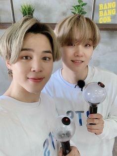 two young men standing next to each other holding magnifying glass balls in their hands