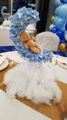 a teddy bear sitting on top of a cloud filled vase with blue and white flowers