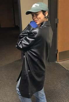 a woman in black jacket and hat holding a cell phone to her ear while standing next to an open door