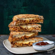 three grilled sandwiches stacked on top of each other with sauce in a bowl next to them