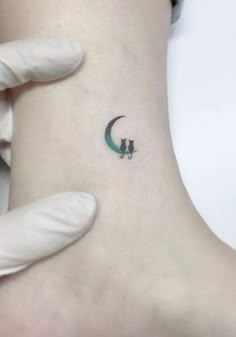 a small tattoo on the ankle of a woman with a cat sitting on top of it