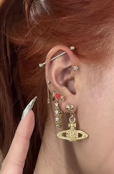 a close up of a person with ear piercings on their ears and one hand holding an object in front of her ear