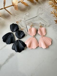 three pairs of black and pink seashell earrings sitting on top of a marble counter