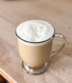 a glass mug filled with liquid sitting on top of a wooden table