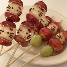 hello kitty skewers on a white plate with green olives and strawberries