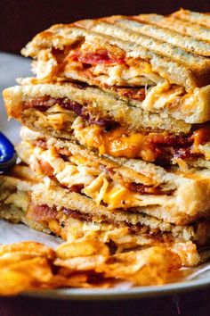 a stack of sandwiches sitting on top of a plate next to a blue and white spoon