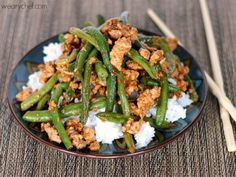 a blue plate topped with green beans and rice next to chopsticks on a table