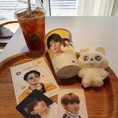 a teddy bear sitting on top of a wooden tray next to two pictures and a drink