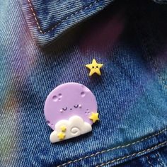 a purple and yellow brooch sitting on top of a blue jean jacket next to a star