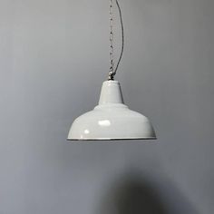 a white light hanging from a ceiling in a room with gray walls and flooring