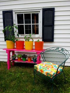 a pink bench with potted plants on it next to a green chair and window