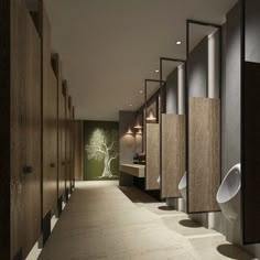 a row of urinals in a bathroom with trees on the wall behind them