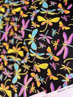 a black background with colorful dragonflies on it