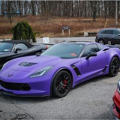 a purple sports car parked in a parking lot next to some other cars and trees