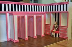 a barbie doll sitting in a pink and black striped room