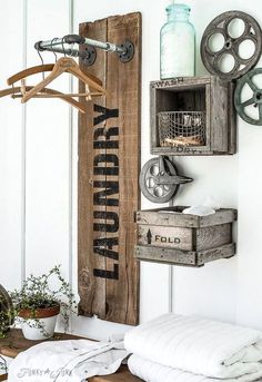 an old wooden sign hanging on the wall next to a bed with pillows and blankets