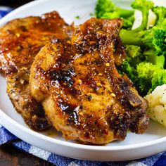 two pieces of chicken and broccoli on a white plate with a blue towel