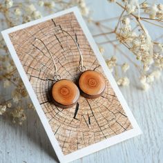 two wooden earrings are sitting on a piece of wood