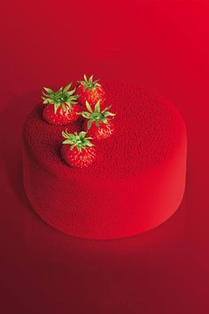 three strawberries sitting on top of a red hat