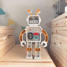 a toy robot sitting on top of a wooden shelf in a room filled with wood planks