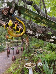 an outdoor garden with lots of plants and decorations hanging from the tree branches, along with a sign that says fairy forest