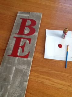 a piece of paper with the word b e on it next to some paint and pencils