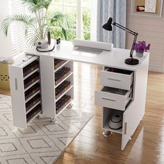 a white desk with drawers and a computer on it in a living room next to a window