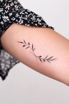 a woman's arm with a small flower tattoo on the left side of her arm