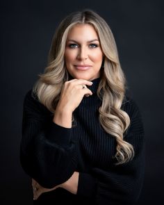 a woman with long blonde hair posing for a studio photo in front of a black background