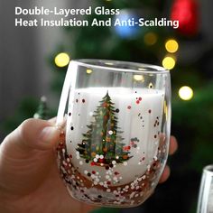 a hand holding up a wine glass with a christmas tree painted on the inside and bottom