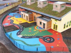 an aerial view of a building with a green roof and colorful mural on the ground