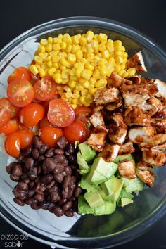 a plate filled with meat, vegetables and corn on the cob next to black beans