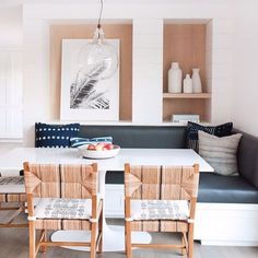 a white table with two chairs and a bowl of fruit on it