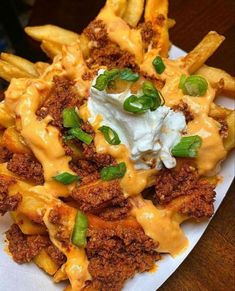 a white plate topped with cheesy fries covered in sauce