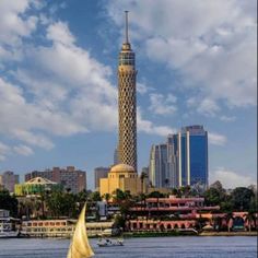 a sailboat in the water near a tall building