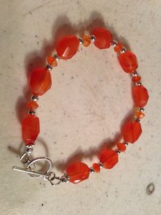 This orange bracelet created by Jewelry By Luet and Co is made of:  orange carnelian gemstones, sterling silver:   beads, toggle clasp and findings.  This bracelet measures 7 1/2 inches. WE OFFER FREE SHIPPING WITHIN THE UNITED STATES. All of our jewelry is unique and custom designed.  We would love to assist you with any custom orders or needs for special occasions! We appreciate you shopping with Jewelry By Luet and Co and hope you will do so often!  See more items from my shop: http://www.ets Handmade Orange Agate Beaded Bracelets, Spiritual Carnelian Orange Bracelets, Spiritual Orange Carnelian Bracelets, Adjustable Carnelian Jewelry With Faceted Beads, Adjustable Orange Gemstone Bracelets, Orange Agate Gemstone Bracelets, Adjustable Carnelian Orange Jewelry, Handmade Silver Carnelian Beaded Bracelets, Orange Carnelian Gemstone Bead Bracelets