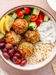 a bowl filled with meatballs, rice and veggies on top of a table