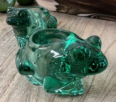 two green glass animals sitting on top of a wooden table