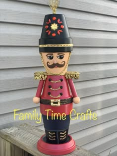 a red and black nutcracker statue sitting on top of a wooden fence