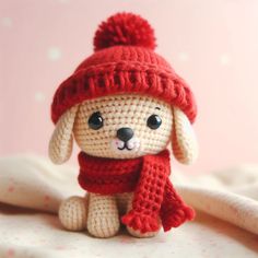 a crocheted dog wearing a red hat and scarf sitting on top of a bed