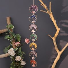 a tree branch with flowers and a wind chime hanging from it's side