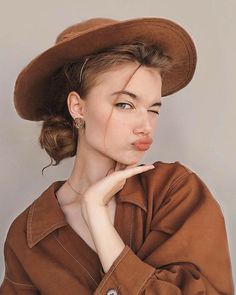 a woman wearing a brown hat with her hand on her chin