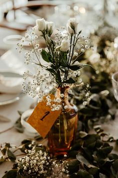 there is a vase with flowers in it on the dining room table set for an event