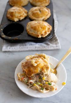 chicken pot pie on a white plate with a spoon in front of it and muffin tins to the side