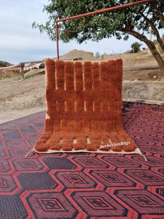 an orange rug on the ground in front of a tree